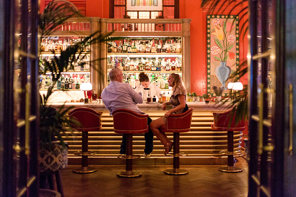 Man and woman talking sat at The Coral Room bar at The Bloomsbury
