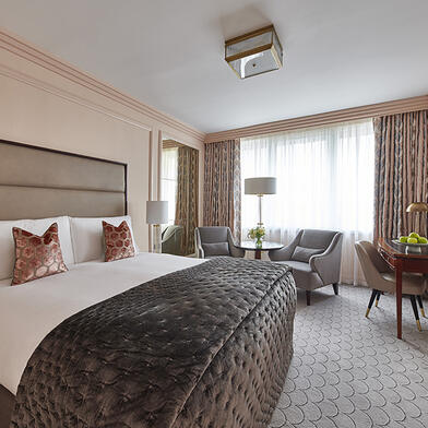 Sun-drenched classic king room at The Westbury Hotel, showcasing a king bed and twin armchairs.
