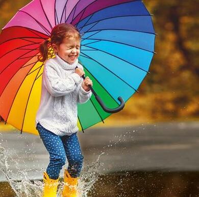 girl with umbrella jumping in puddle