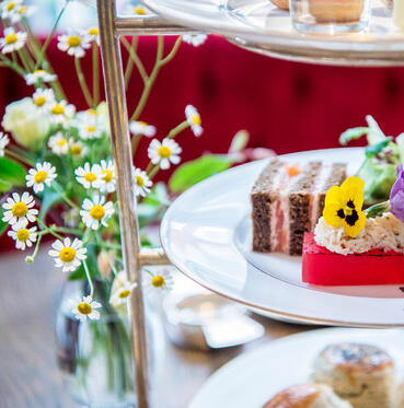 afternoon tea served on a tiered cake stand with a bunch of daisies