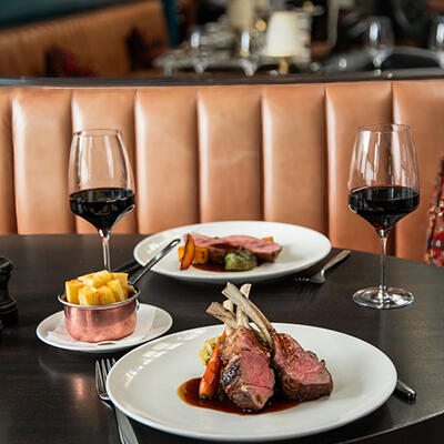 Delicious T-bone steak served with golden chips and a pair of red wine glasses at River Grille restaurant.